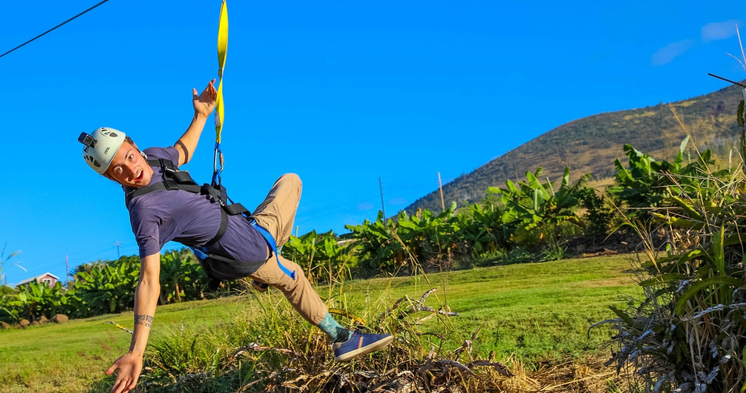 man zip lining across a farm in Maui